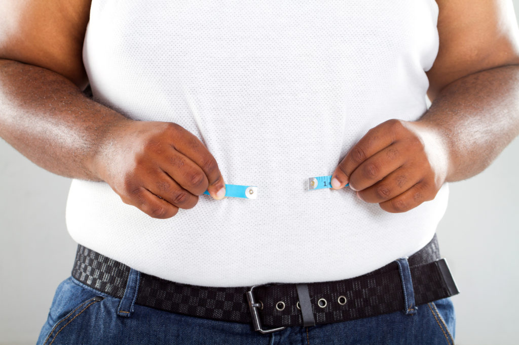 overweight african american man measuring waist